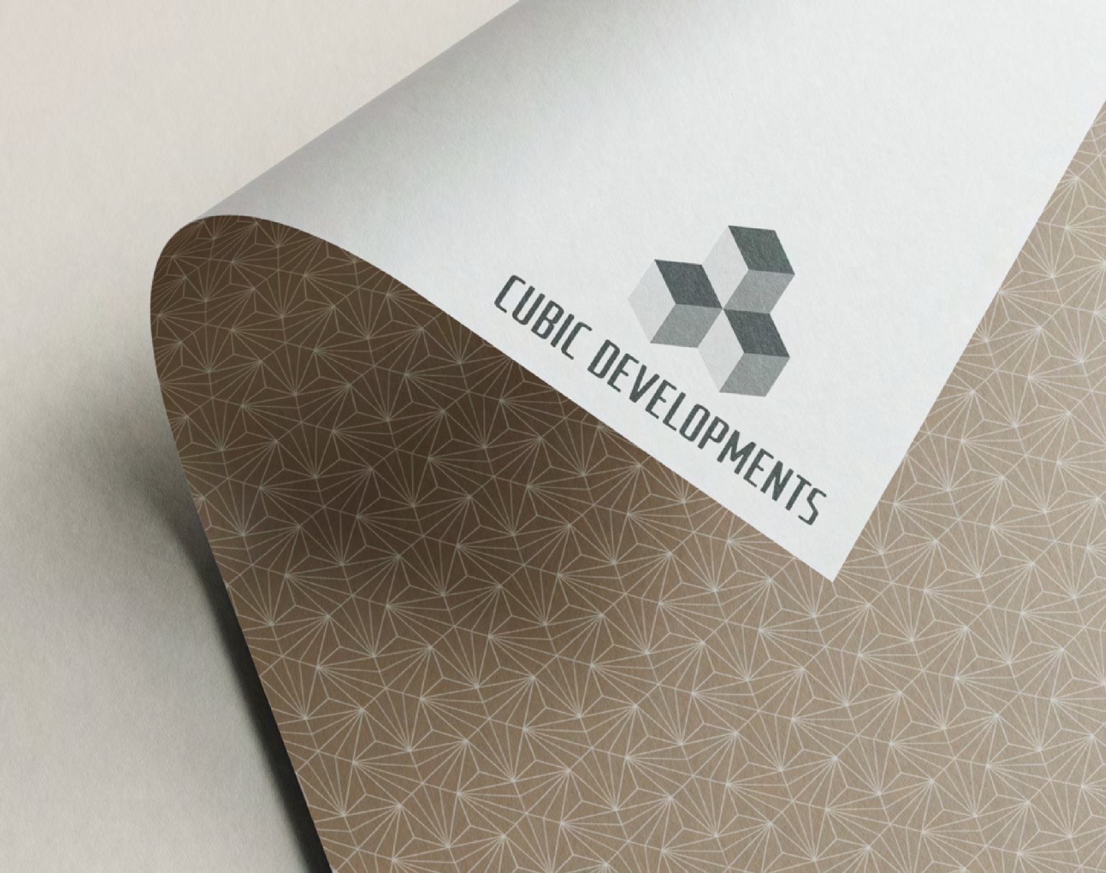 The Cubic Developments cube mark printed on a curling sheet of patterned paper.