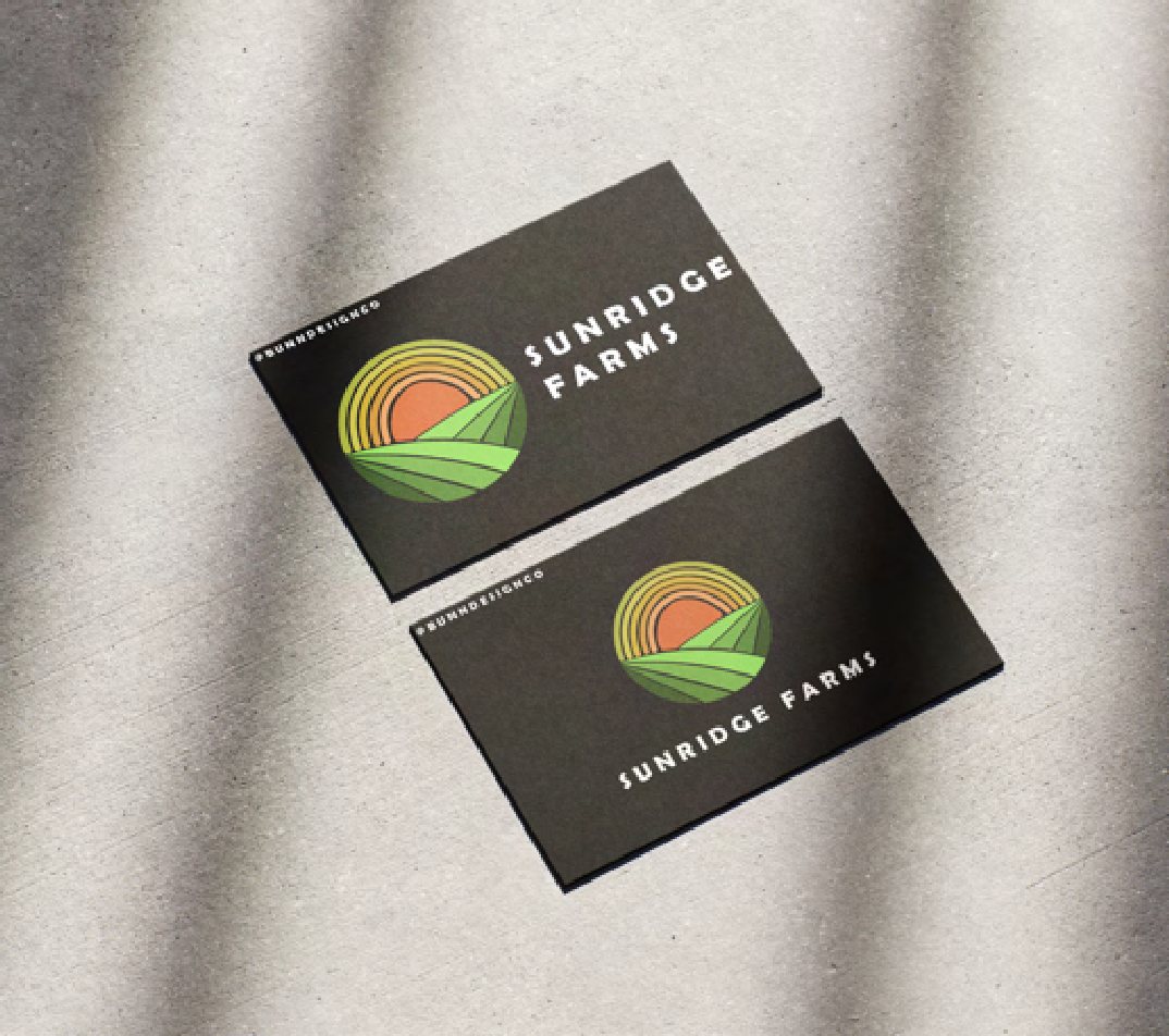 Two dark Sunridge Farms business cards on fabric, showing a sunrise-over-field logo.