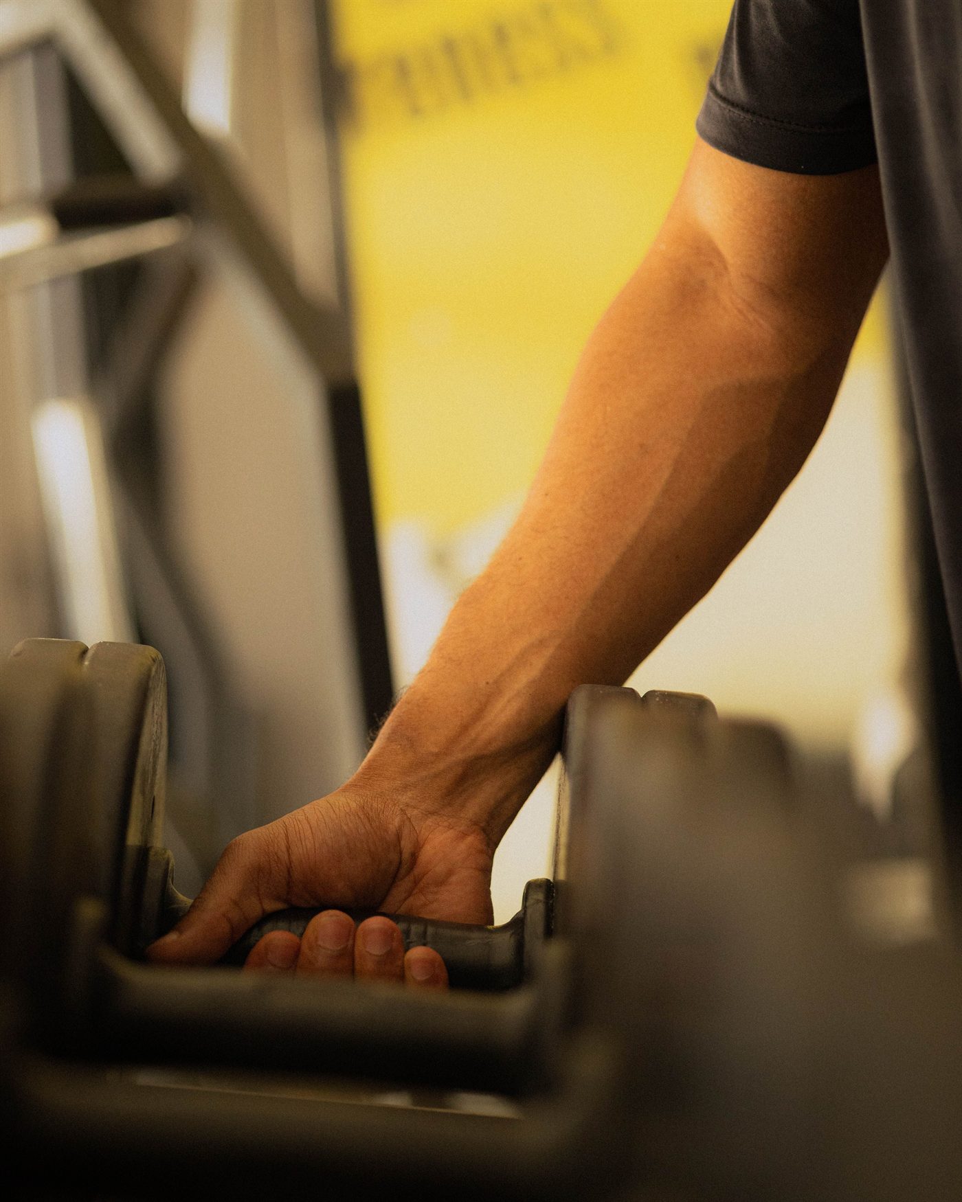 A member reaching for a dumbbell on the rack.